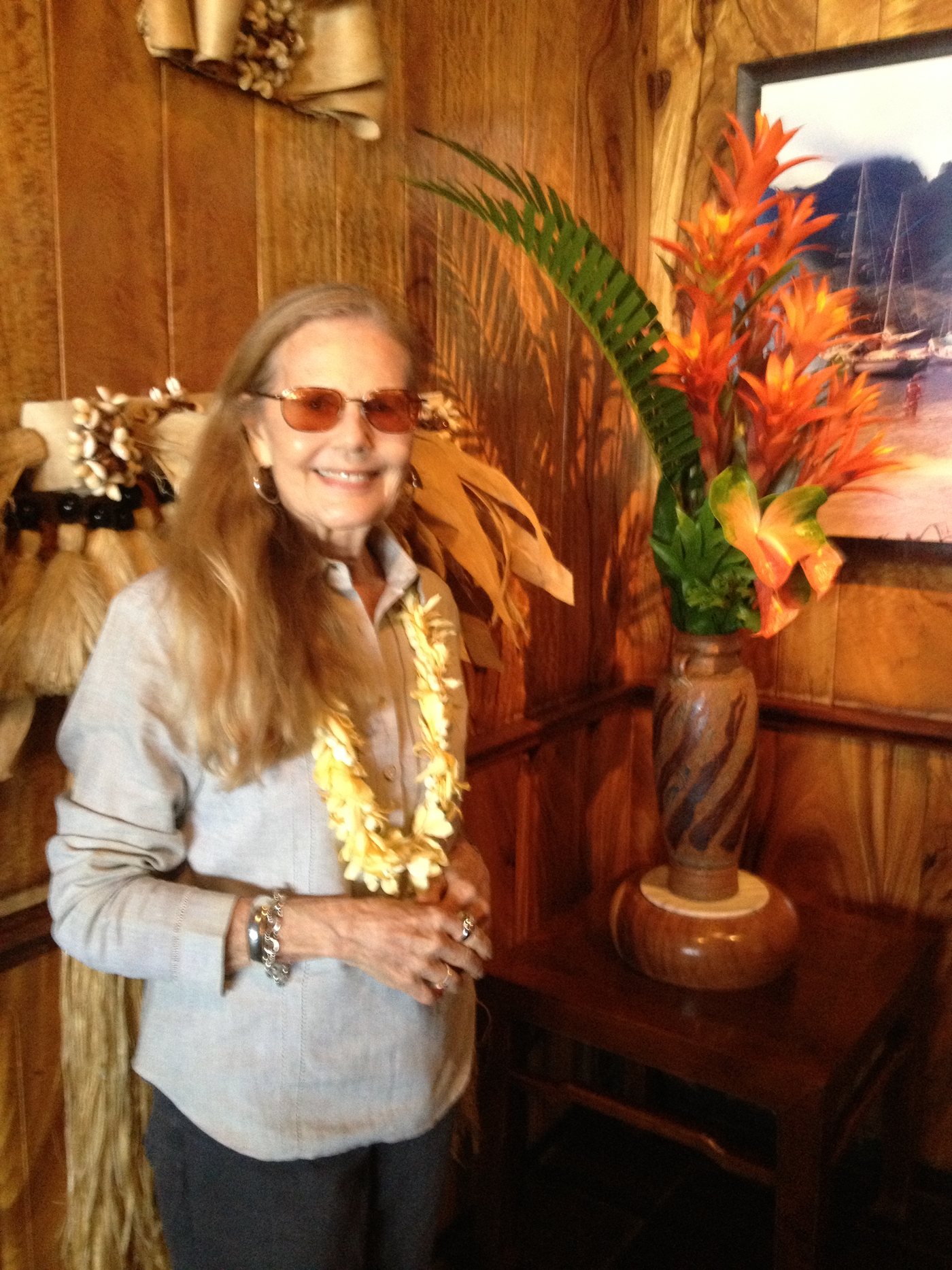 Nancie Caraway wearing a lei in a koa-paneled room