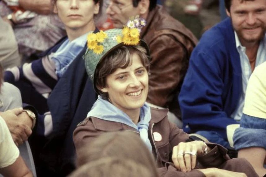 Petra Kelly smiling in a crowd, flowers tucked in her helmet