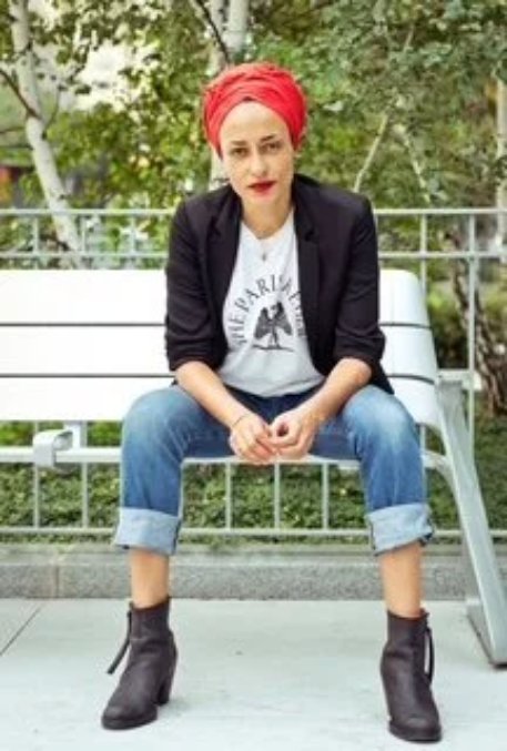 Zadie Smith in a red beret, seated on a park bench